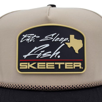 Close up of a beige cap with a 'Skeeter' logo, the text 'eat, sleep, fish', and a Texas map on a black rubber patch on the front. 